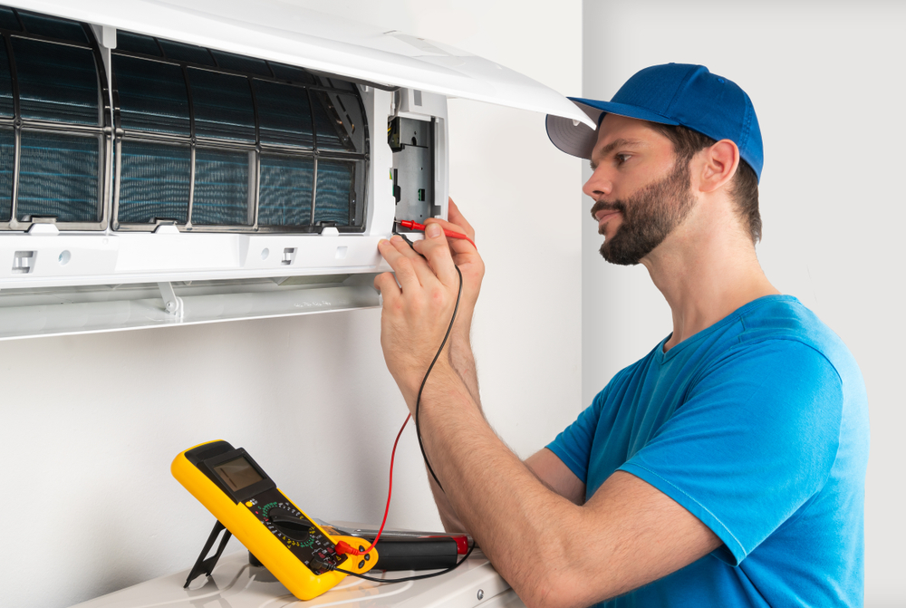 AC technician servicing a central air unit in a Cayman Island home