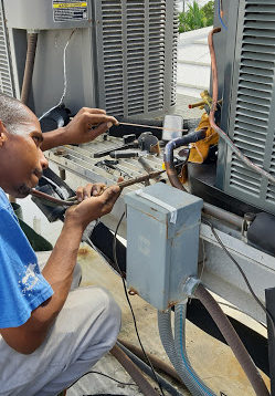Air conditioning contractor performing routine maintenance services on a AC unit in a home in the Cayman Island