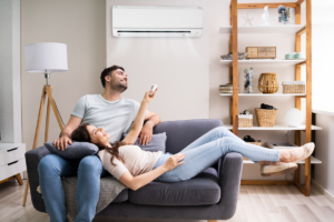 Couple sitting in the living room turning mini-split unit on with remote control.