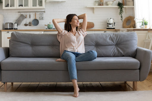 A woman smiling as she relaxes on a couch.