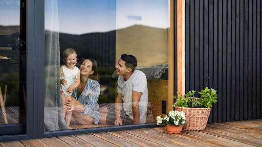 A woman, man, and child smiling as they sit and look out a window.