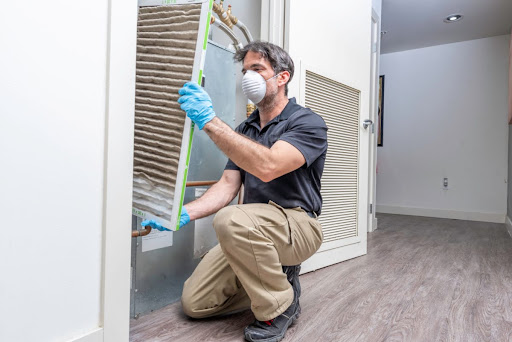 A man replacing an HVAC system's air filter.