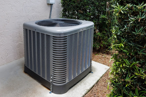 An AC condenser unit installed on a slab of concrete.