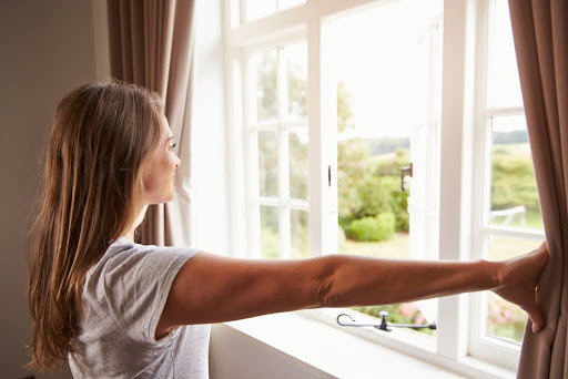 Woman opening shades of window