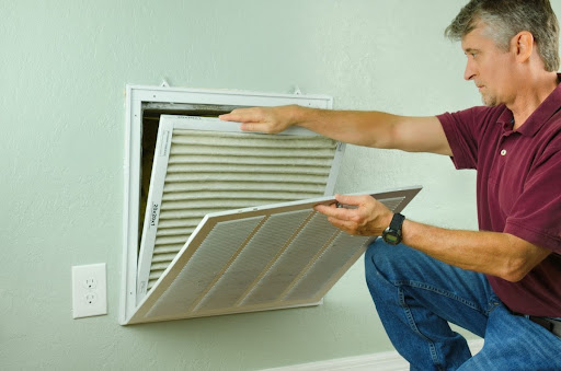 A man replacing an AC air filter.