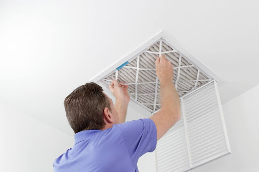 A man replacing an HVAC air filter.